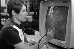 A woman uses a “light pen” to draw a design on a display terminal