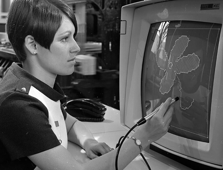 A woman uses a “light pen” to draw a design on a display terminal