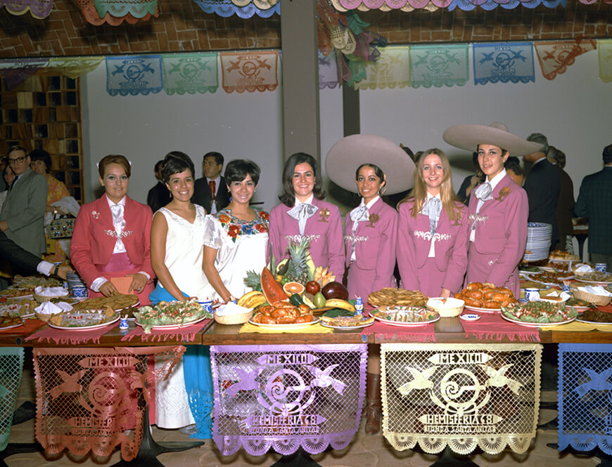 Group with platters of food on serving table in Mexico Pavilion